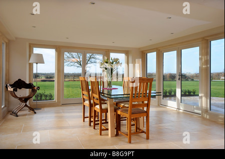 EIN ESSZIMMER UMGEBEN VON TERRASSENTÜREN IN EIN MODERNES LANDHAUS-UK Stockfoto