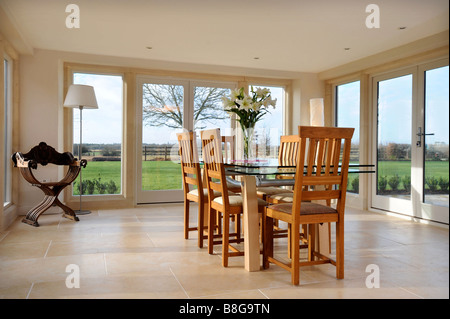 EIN ESSZIMMER UMGEBEN VON TERRASSENTÜREN IN EIN MODERNES LANDHAUS-UK Stockfoto