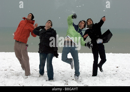 Junge Burschen zu genießen, Schneeballschlachten und Hanteln über während einer seltenen Schneefalls am Strand von Brighton East Sussex UK Stockfoto