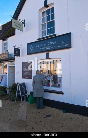 Eine Frau, die in das Fenster von kristallklarer Schönheitsklinik in Long Melford, Suffolk, Uk Stockfoto