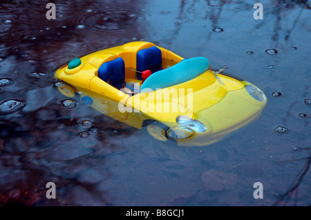 ein Spielzeug Sportwagen in einer Pfütze Wasser sinken. Stockfoto