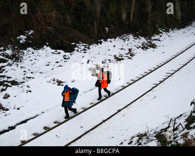 Zwei Männer in orange Warnschutz Jacken zu Fuß auf einer ländlichen Eisenbahnlinie im Schnee Stockfoto
