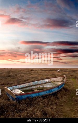 Sonnenuntergang über einem Boot auf Salzwiesen in Burnham Deepdale, North Norfolk, England, UK Stockfoto