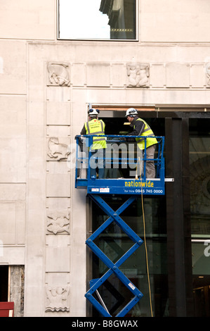 Zwei Bauarbeiter auf eine erhöhte hydraulische Schere heben Plattform, Cheapside, The City of London, England, UK Stockfoto