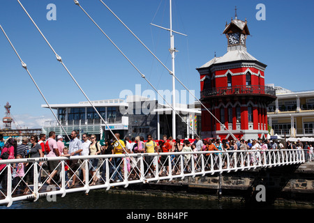 Menschen, überqueren die Schaukel Brücke bei der V & A Waterfront hinter ist der Uhrturm Kapstadt Südafrika Stockfoto