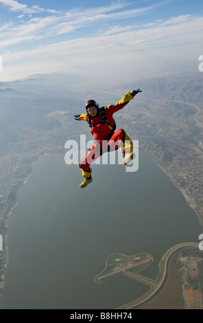 Fallschirmspringer ist Sit fliegen in den blauen Himmel über einem großen See und Spaß haben. Die Wolken-Linie auf der Rückseite ist ein Verweis auf Tauchen. Stockfoto