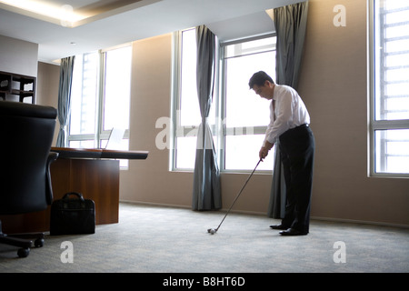 Geschäftsmann, Golfen im Büro Stockfoto