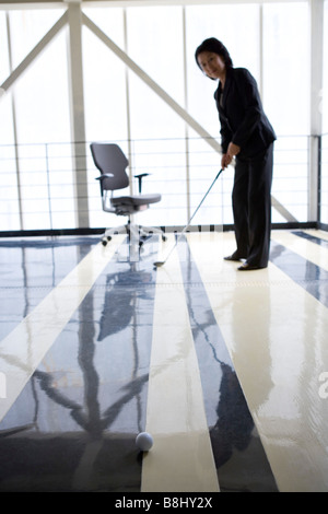 Geschäftsfrau praktizierender Golf im Büro Stockfoto