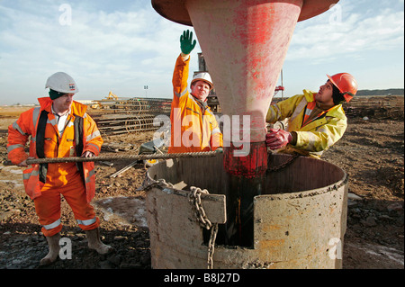 Bauunternehmen Beton in ausgegrabenen Tiefgründung Haufen gießen, nachdem ein Stahl Bewehrungskorb in den Stapel eingefügt wurde. Stockfoto