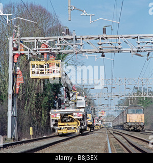 Auftragnehmer auf obenliegende Caternary System hinter teilweise Eisenbahn Blockade, während Züge auf live-Tracks noch ausgeführt werden Stockfoto