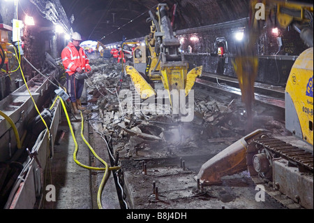 Operativen per remote gesteuert Betonaufbruchhammer Aushub worn-out Deck unter den Gleisen während Schiene Tunnel Upgrade-Projekt. Stockfoto