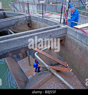 Arbeitnehmer, die Reinigung Schlamm aus einem Reservoir Siedlung auf einer Kläranlage in Südafrika. Stockfoto