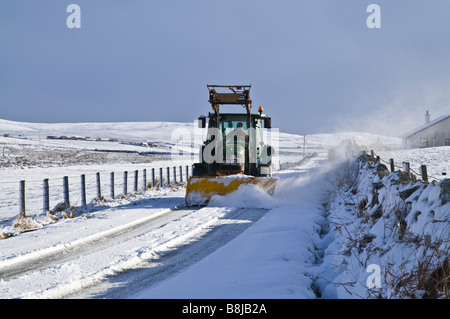 dh ROADS UK Farm Traktor Schneepflug Schneeräumung von Orkney Land Winter Straßen Schneepflug Fahrzeug Pflug verschneite Spur Straße Stockfoto