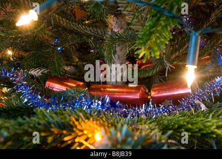 Dekorationen und Christmas Cracker eingebettet in Filialen von echten Weihnachtsbaum Heiligabend England hautnah Stockfoto