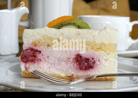 Frisches Obst-Torte auf eine Platte mit einem silbernen Kuchen Gabel Cup und Milch Krug im Hintergrund Stockfoto