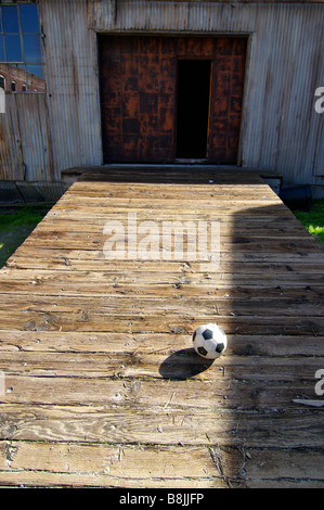 Ein Fußball sitzt auf einer alten Laderampe wartet ein Spiel von Futbol. Stockfoto