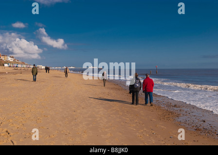 Menschen, die an einem schönen Tag Southwold Strand entlang spazieren Stockfoto