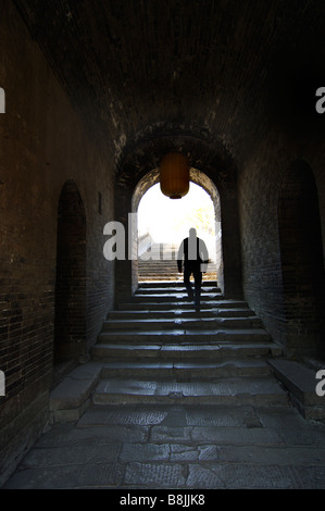 Ein Mann geht dann die Treppe durch einen alten steinernen Flur. Stockfoto
