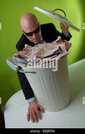 Mann im Anzug mit Mülleimer voller Euro Geld. Stockfoto