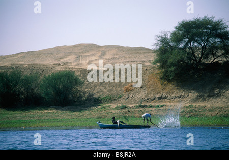 Südlichen Nil Boot mit zwei Männern Angeln gegen Wasser Sand grüne Vegetation durch Fluss Rand der Nil Ägypten Stockfoto