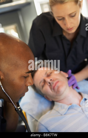 Sanitäter mit Stethoskop auf Patienten in der Ambulanz Stockfoto