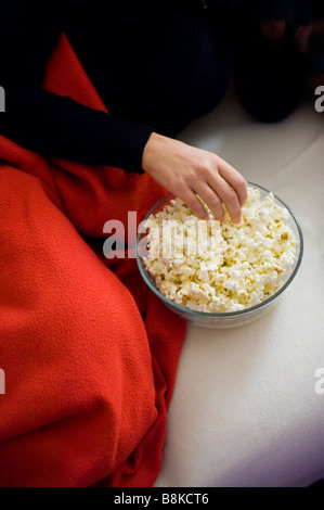 Frau Essen Popcorn auf dem sofa Stockfoto