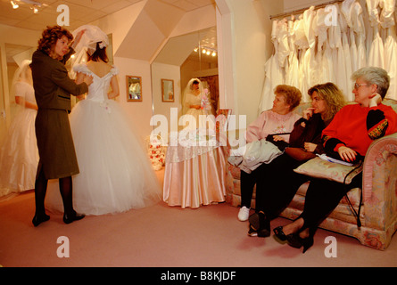 Lakeside Shopping Centre Thurrock Essex UK einer Braut zu werden versucht auf ein Brautkleid, während ihre Familie Uhren Stockfoto