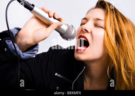 Junge weibliche karaoke Sänger singt Musik am Mikrofon Stockfoto