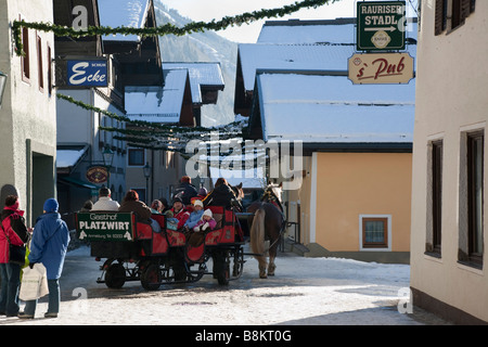 Rauris Rauriser Sonnen Tal Österreich Touristen auf Pferd gezogenen Schlitten fahren Sie durch das Alpenresort mit Schnee im winter Stockfoto