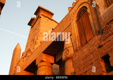 Ägypten, Luxor-Tempel-Ruinen, [niedrigen Winkel] Ansicht der Moschee Mauer, ersten Pylon und Obelisk von orange Leuchten Sonnenuntergang beleuchtet Stockfoto