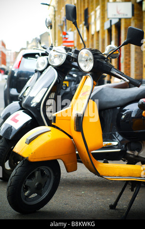 Eine Linie der Vespa Roller in Shorditch, East London, am Straßenrand mit einem Stadt-Hintergrund. Stockfoto