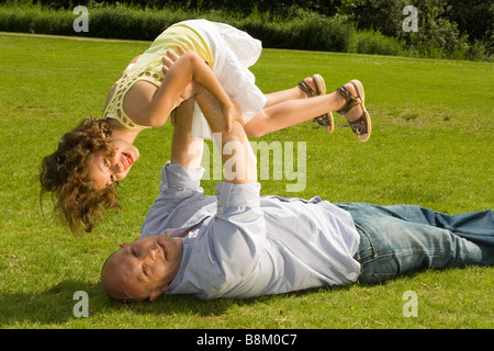 Kleines Mädchen von ihrem älteren Daddy im Park hoch gehalten Stockfoto