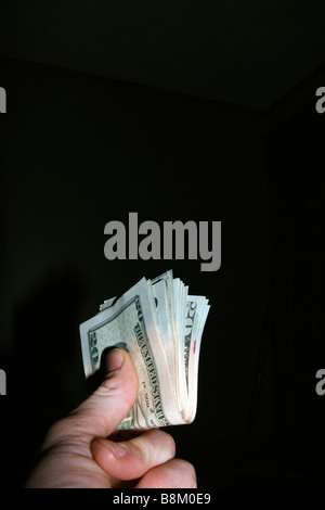 Linke Hand, die gefalteten USA zwanzig-Dollar-Scheine auf schwarz. Stockfoto