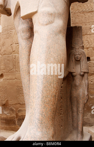 Kleine Steinskulptur der Königin Nefertari stehend an den Füßen einer kolossalen Statue von Pharao Ramses II, Luxor-Tempel, Ägypten Stockfoto