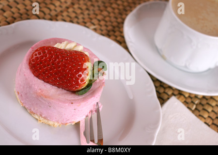 Frische Erdbeer Torte mit halben Frucht auf der Oberseite und eine Tasse heißen cappuccino Stockfoto