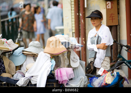 Frau verkaufen Hüte auf einer Straße in Shanghai, China Stockfoto