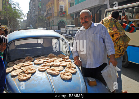 KAIRO, ÄGYPTEN. Ein Mann verkauft Fladenbrot ('Aish Shamsi) von der Motorhaube von einen alten VW Käfer auf einer belebten Straße im Zentrum von Kairo. 2009 Stockfoto