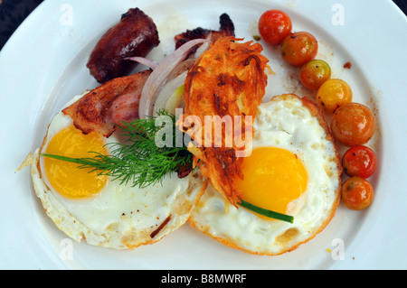 Frühstück, Teller mit Spiegelei, Speck, Würstchen und Tomaten Stockfoto