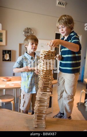 zwei Jungs zusammen arbeiten, wird versucht, einen hohen Turm aus Holzklötzen bauen Stockfoto