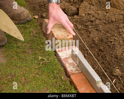 Verlegung einer Backstein Kante Garten Rasen Stockfoto