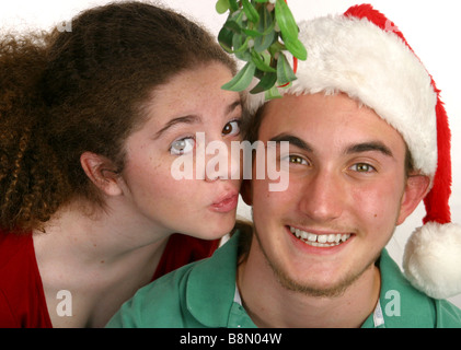 Ein junges Mädchen küssen ein Teenager junge unter dem Mistelzweig Weihnachten Stockfoto