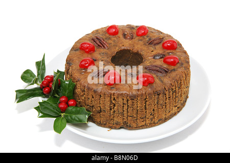 Schöne Weihnachten Früchtekuchen, garniert mit Kirschen Pekannüsse und einen Zweig der Stechpalme isoliert auf weißem Hintergrund Stockfoto