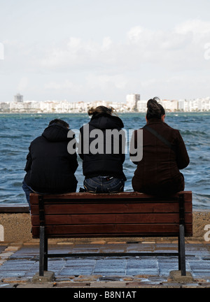 Drei Menschen Freunde sitzen beisammen sitzen auf einer Bank Gesicht aussehen aussehende zugewandten Ägäische Meer Golf von Izmir Türkei von hinten gesehen Stockfoto