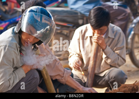 Vietnamesische genießen Sie eine traditionelle Wasserpfeife rauchen, mit einem kostenlosen Tester des lokalen Tabaks auf Bac Ha Markt in Vietnam. Ethnischen Minderheit Wochenmarkt Stockfoto