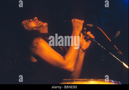 Eine Musikerin wirft den Kopf zurück während des Singens in ein Mikrofon bei einem inszenierten Pop-Konzert. Stockfoto