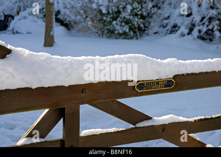 Neuschnee am oberen Leiste der Tor, das Messing Schild hat "Schließen das Tor" Stockfoto