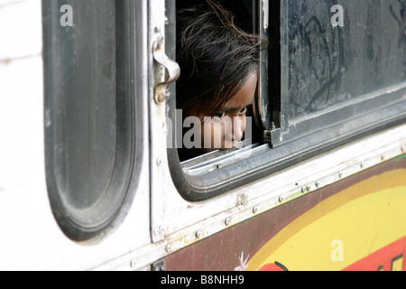 Junges Mädchen schaut aus einem Busfenster in Indien Stockfoto
