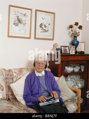 Ältere blinde Dame zu Hause, die ein Hörbuch auf einem Sony Walkman-Kassettenrekorder hört, UK Stockfoto