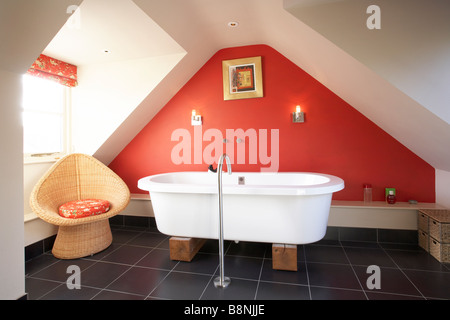 Innenausbau Badezimmer im Dach Dachboden mit moderne freistehende Badewanne auf Holzblöcke schwarz rote Wand Schiefer Boden Stockfoto