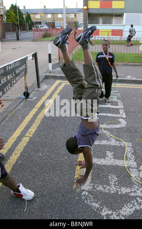 Ein Kind macht einen Handstand beim Spielen mit Freunden auf der Straße. Stockfoto